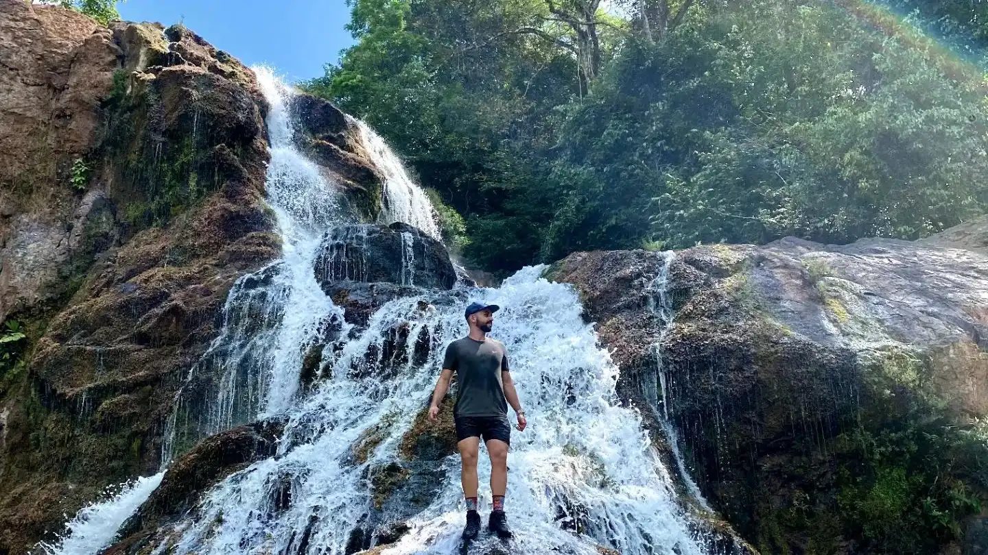 Un uomo in piedi davanti a una cascata