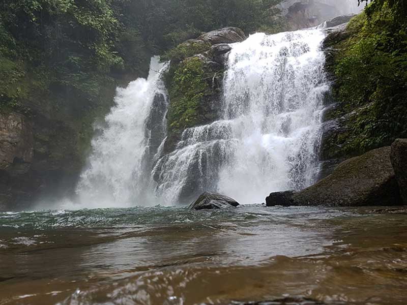 Un uomo in piedi in un fiume accanto a una cascata.