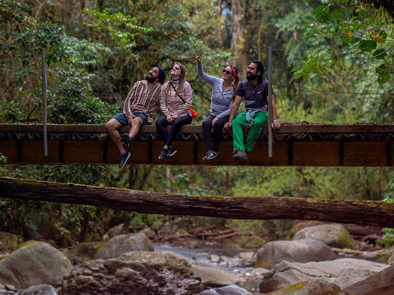Un gruppo di persone sedute su un ponte sopra un fiume.