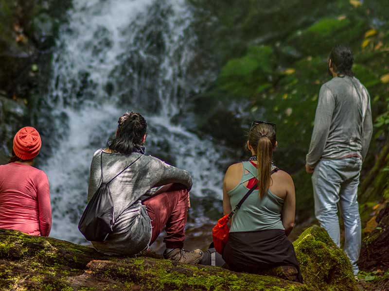 Un gruppo di persone sedute su una roccia che guardano una cascata.