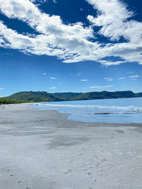 Una persona che cammina su una spiaggia con una tavola da surf.