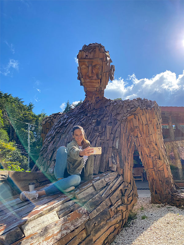 Una donna seduta in cima a una scultura di legno.