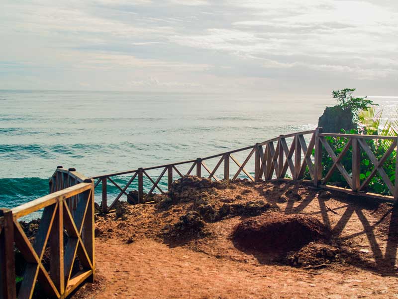 Una passerella di legno che conduce all'oceano in una giornata nuvolosa.