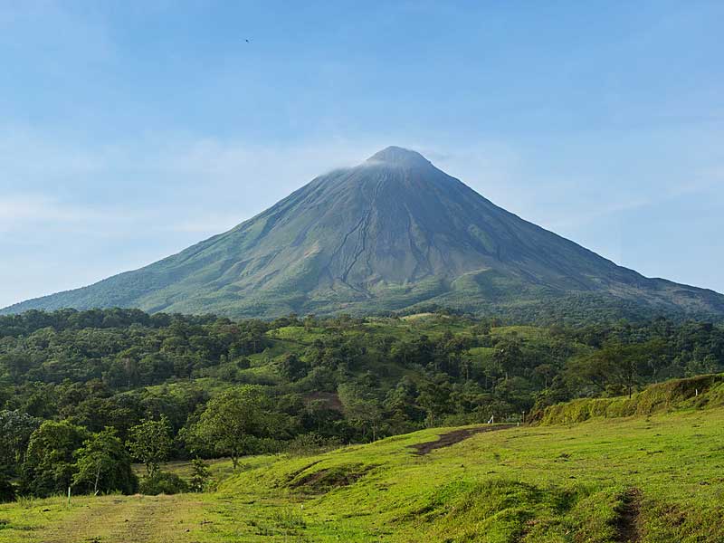 Un campo verde con una montagna sullo sfondo.