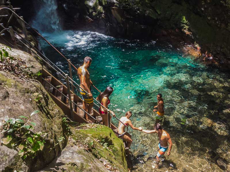 Un gruppo di persone in piedi in cima a una scogliera accanto a una cascata.