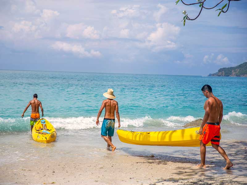 Un gruppo di persone su una spiaggia con una tavola da surf gialla.
