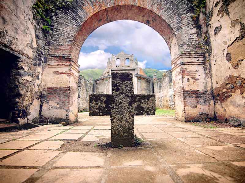 Una croce di pietra al centro di un cortile.