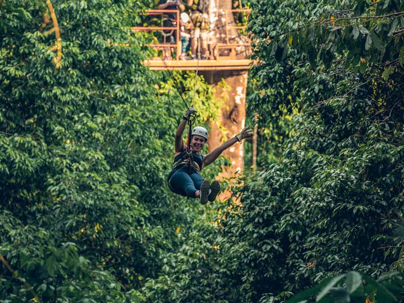Una donna che percorre una teleferica nel mezzo di una foresta.