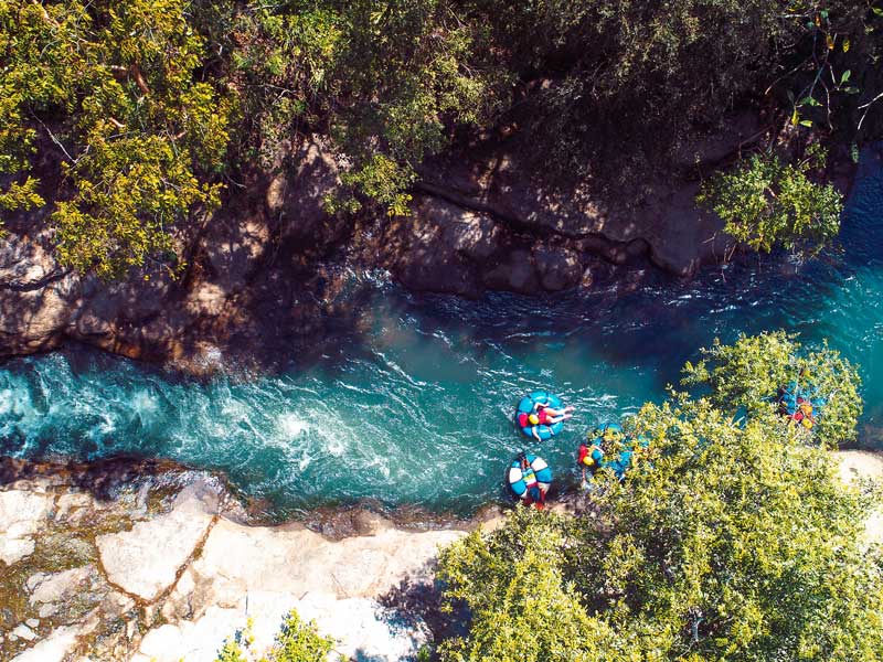 Un gruppo di persone in zattera che pagaia lungo un fiume.