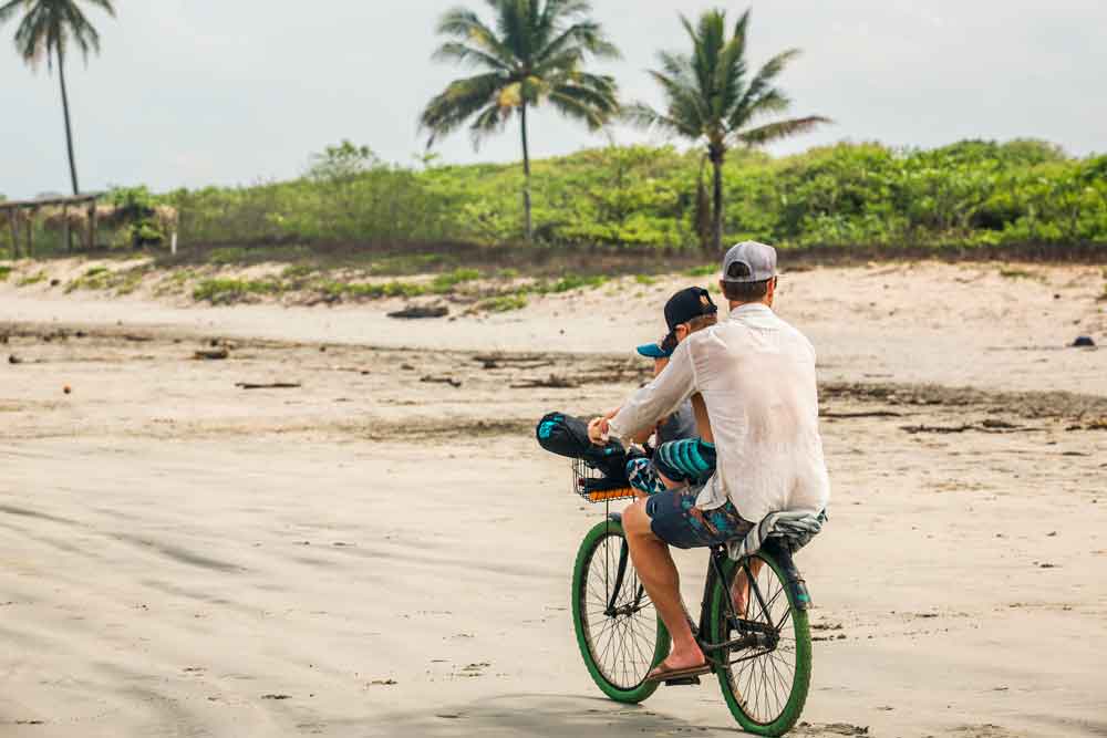 Un uomo e un ragazzo in bicicletta su una spiaggia.