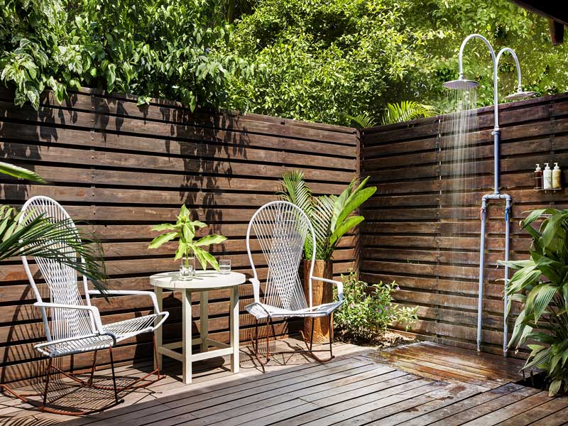 Una terrazza in legno con due sedie e un tavolo.