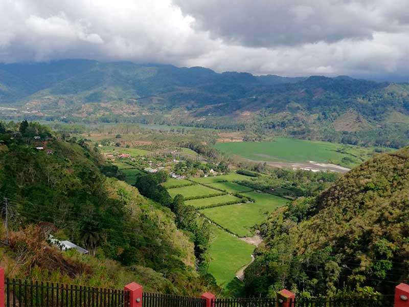 Una valle verde e lussureggiante circondata da montagne sotto un cielo nuvoloso.