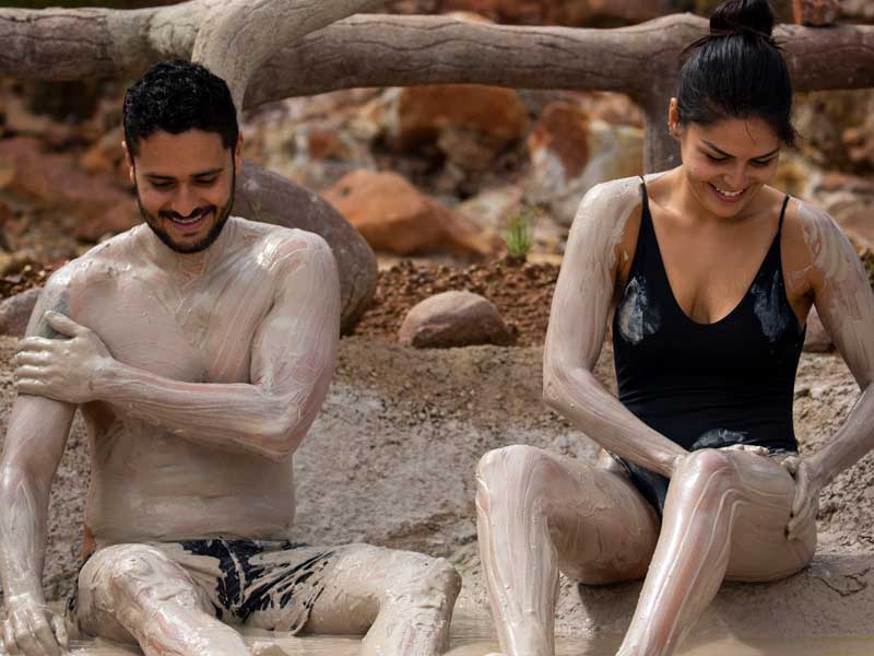 Un uomo e una donna coperti di fango seduti a terra.