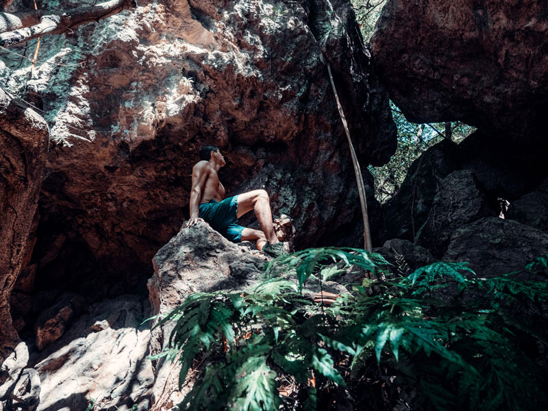 Un uomo seduto in cima a una roccia vicino a una foresta.