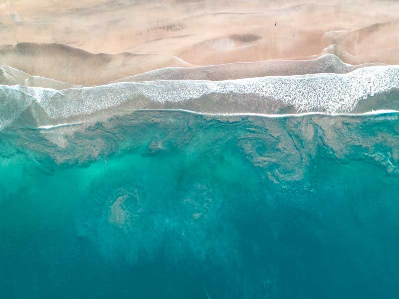 Vista aerea di una spiaggia sabbiosa e dell'oceano.