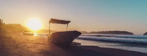 La vista del tramonto e dell'oceano con la barca adagiata sulla spiaggia