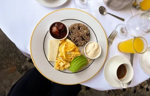 un piatto con la colazione su un tavolo, con accanto un caffè e un succo d’arancia