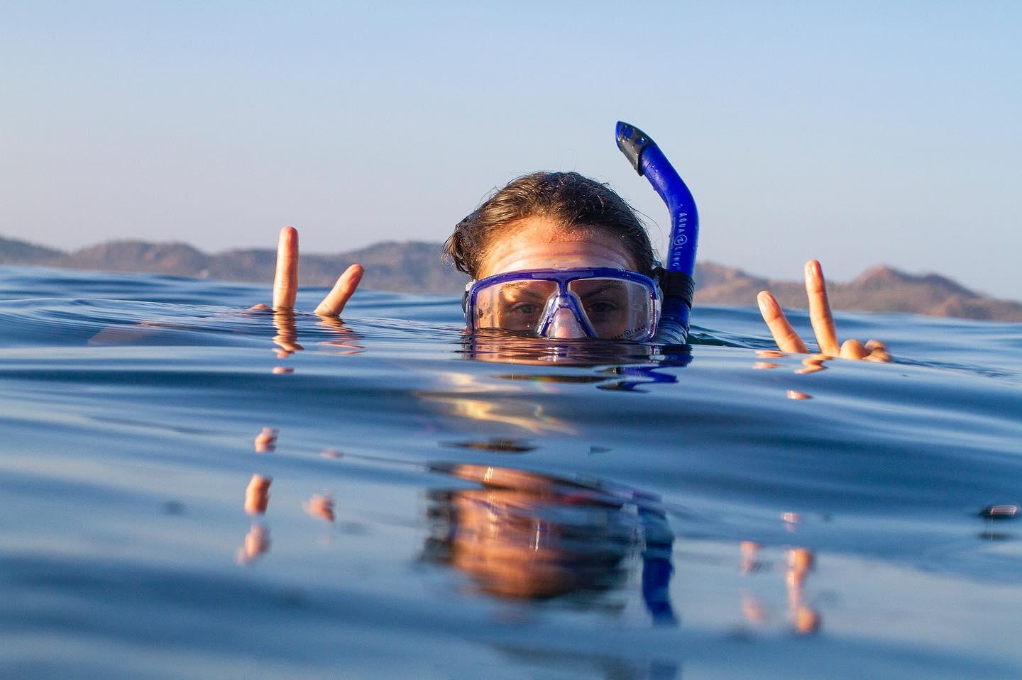 donna con segni di pace che fa snorkeling