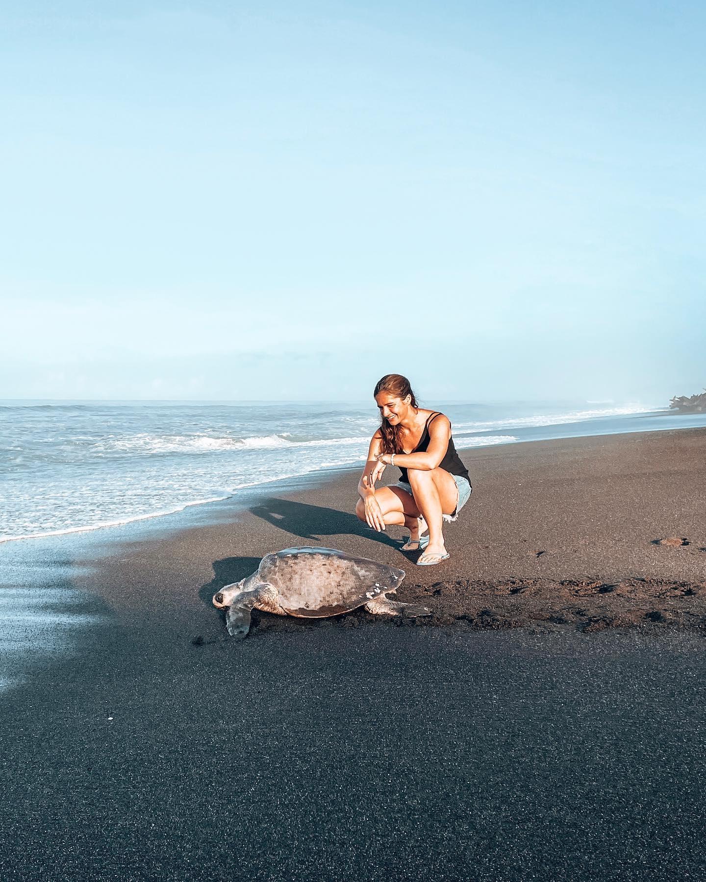 Una donna vicino a una tartaruga su una spiaggia