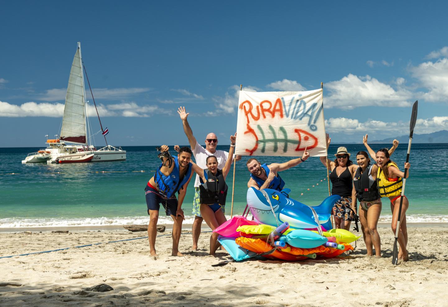 Persone sulla spiaggia con un cartello pura vida