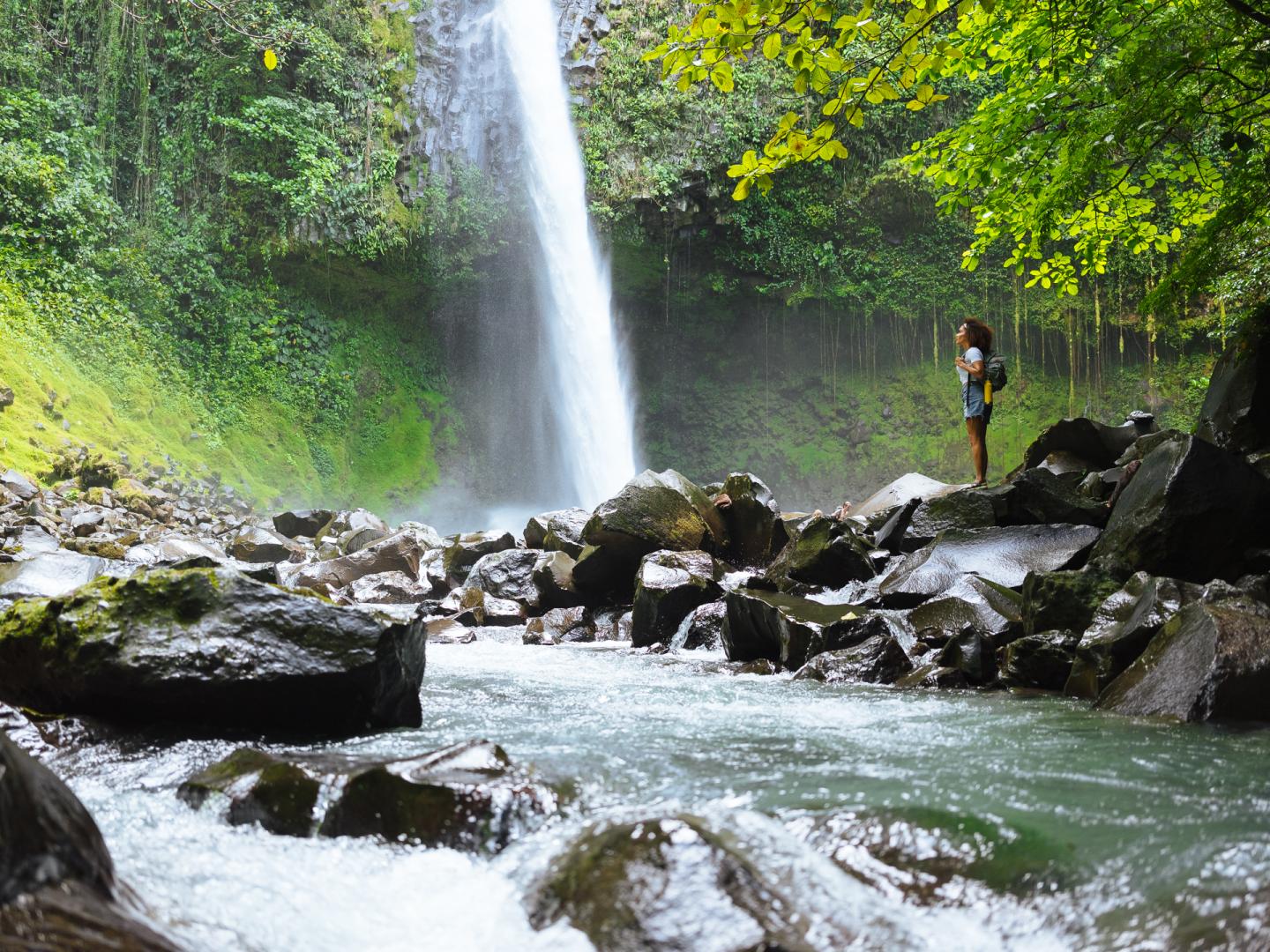 Donna in piedi accanto a una cascata nella giungla