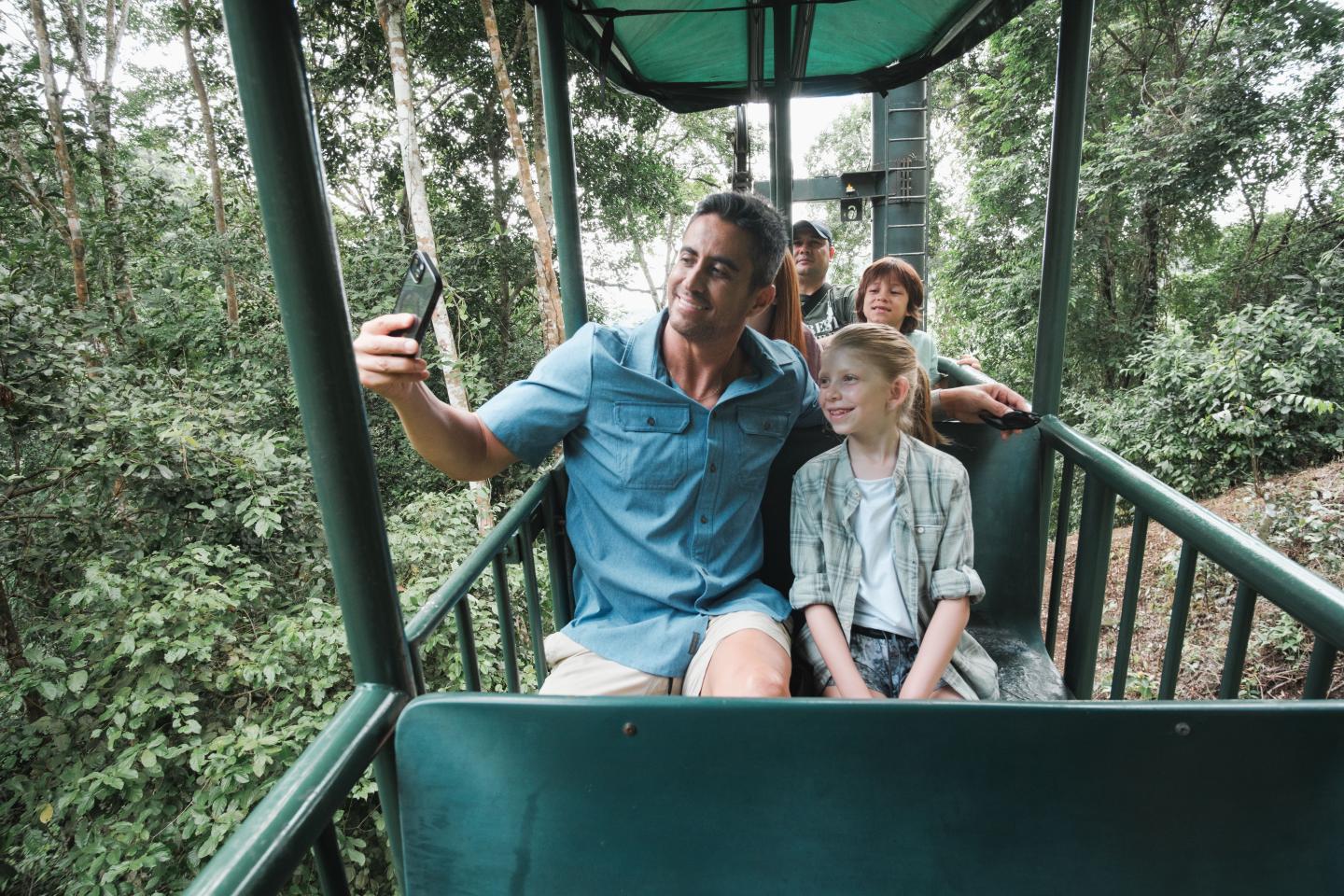 Una famiglia che si scatta un selfie in una gondola all'aperto sopra la chioma della foresta pluviale.